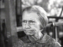 a black and white photo of an older woman with glasses