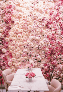 a table and chairs in front of a wall covered in pink roses