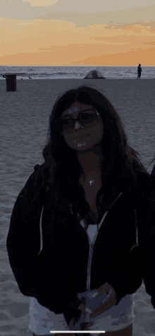 a woman wearing sunglasses and a cross necklace is standing on a beach