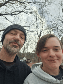 a man and a boy are posing for a picture and the boy is wearing a grey hoodie