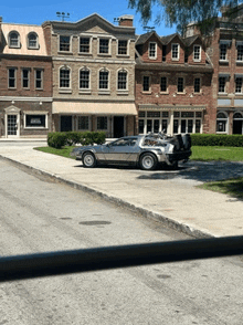 a silver car is parked on the side of the road in front of a brick building