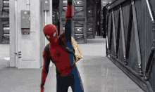 a man in a spiderman costume is standing in a hallway with his arm up .
