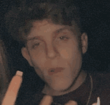 a close up of a young man 's face with a cigarette in his mouth .