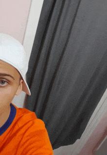 a young boy wearing a white hat and an orange shirt