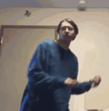 a young man in a blue sweater is dancing in a room .