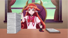 a girl with red hair and horns is sitting at a desk with a stack of papers