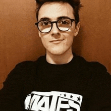 a young man wearing glasses and a black shirt with the word mates on it .