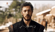 a man with a beard is standing in front of a building with arabic writing .