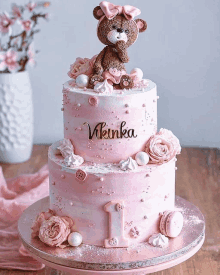 a pink cake with a teddy bear on top has the name vianka on it