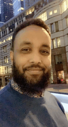 a man with a beard is smiling for the camera in front of a building