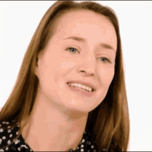 a close up of a woman 's face with a smile on her face and a black and white polka dot shirt .