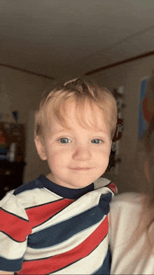 a little boy wearing a striped shirt looks at the camera