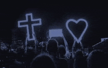 a crowd of people standing in front of a stage with a cross and heart .