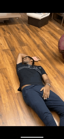 a man in a black shirt is laying on the floor with his hands on his head