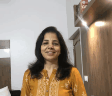 a woman in a yellow shirt stands in front of a shelf with books on it that says ca