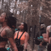 a woman in an orange tank top is standing in the woods