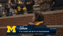 a man wearing headphones stands in front of a banner that says blake corum on it