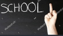 a person is pointing at the word school on a blackboard .