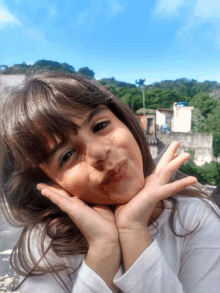 a young girl making a funny face with her hands on her chin