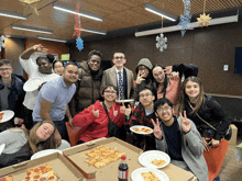 a group of people posing for a picture with pizza boxes