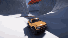 a yellow ford bronco is driving through a snowy area