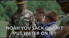 a man in a military uniform is talking to a group of young boys while they are standing in a field .