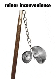 a metal object is hanging from a wooden pole with a chain .