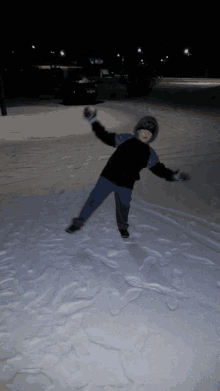 a young boy is playing in the snow at night with a walgreens in the background