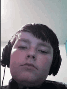 a young boy wearing headphones looks at the camera