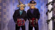 two men in suits and hats are holding gifts .