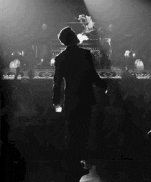 a man in a suit is smoking a cigarette in front of a crowd in a black and white photo .