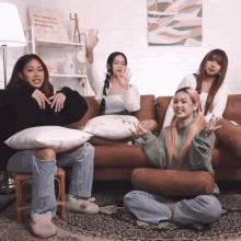 a group of women sitting on a couch with a sign on the wall that says " the smallest things are the most brightest "