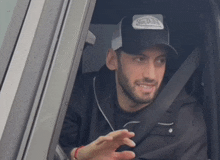 a man wearing a vans hat is sitting in the driver 's seat of a car