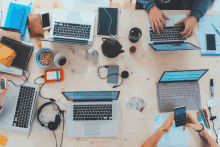 a group of people sitting around a table with laptops