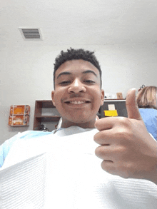 a young man in a dental chair gives a thumbs up sign