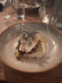 a plate of food on a table with a glass of water and a candle