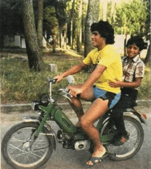 a man in a yellow shirt is riding a motorcycle with a boy on the back .