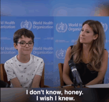 a boy and a woman are sitting in front of a world health organization wall