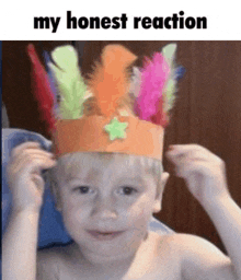 a young boy wearing a paper crown with feathers and a star on it .