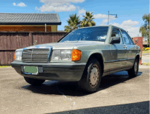 a green mercedes is parked in a driveway