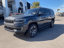 a gray jeep grand cherokee is parked in front of a dealership