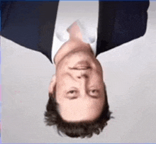 a man wearing a suit and tie is upside down .