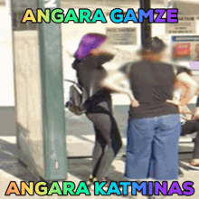 a woman with a purple scarf on her head is standing in front of a sign that says angara gamze angara katinas