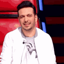 a man wearing a white jacket and a grey shirt with a hand on it