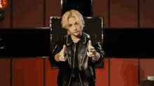 a man in a leather jacket is holding a red heart shaped object in his hands .