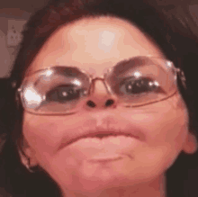 a woman wearing glasses and making a funny face .