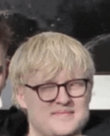 a close up of a man wearing glasses and blonde hair making a funny face .