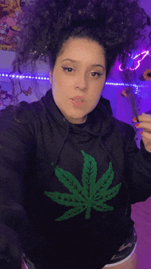 a woman in a black hoodie with a green marijuana leaf on it