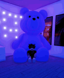 a person is sitting in front of a giant blue teddy bear