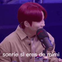 a man with red hair is smiling in front of a microphone with the words sonrie si eres de mimi written on the bottom